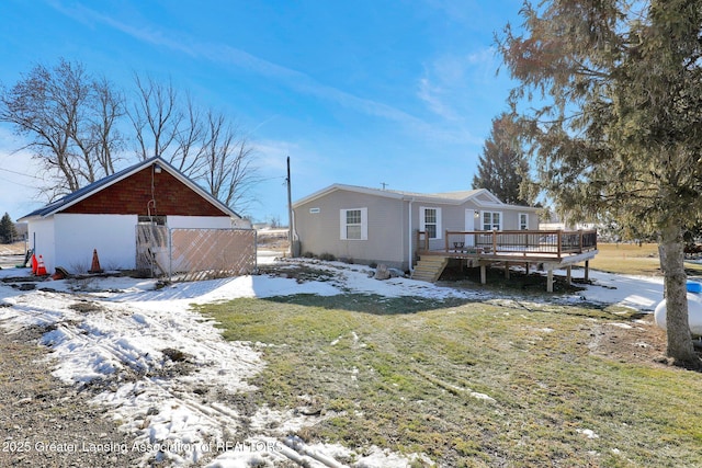 snow covered property featuring a wooden deck and a yard