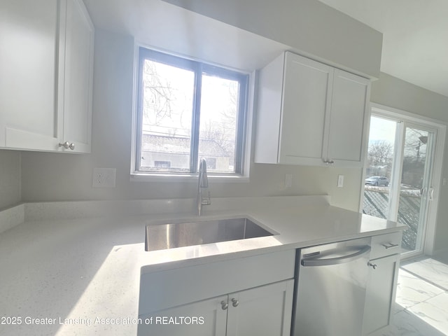 kitchen with sink, a wealth of natural light, stainless steel dishwasher, and white cabinets