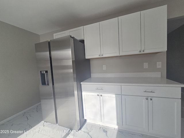 kitchen featuring stainless steel fridge and white cabinets