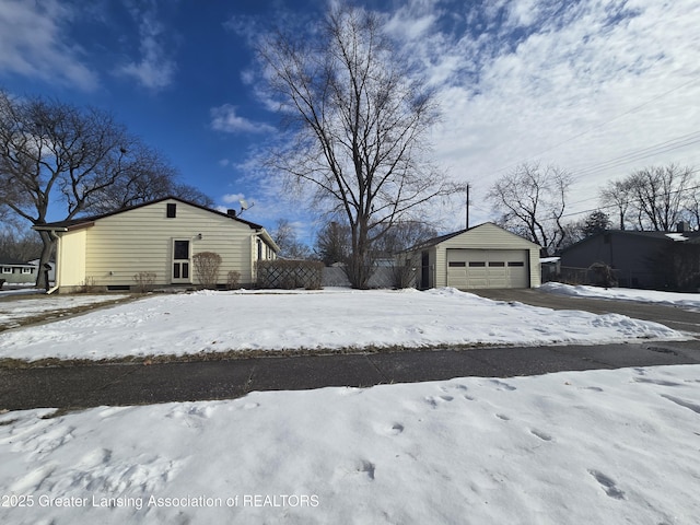 snowy yard featuring an outbuilding and a garage