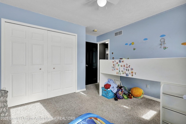 unfurnished bedroom featuring a textured ceiling, a closet, ceiling fan, and carpet flooring