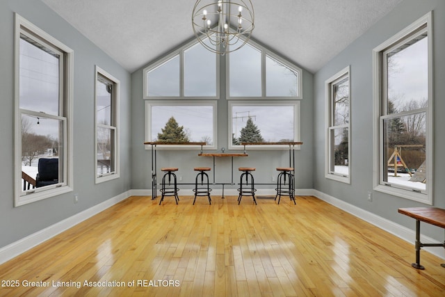 sunroom featuring vaulted ceiling and a chandelier