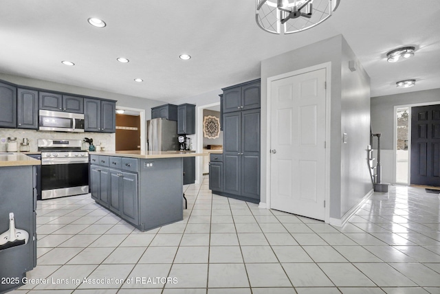 kitchen featuring backsplash, appliances with stainless steel finishes, a kitchen breakfast bar, and light tile patterned floors