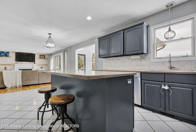 kitchen with light tile patterned floors, backsplash, hanging light fixtures, and sink