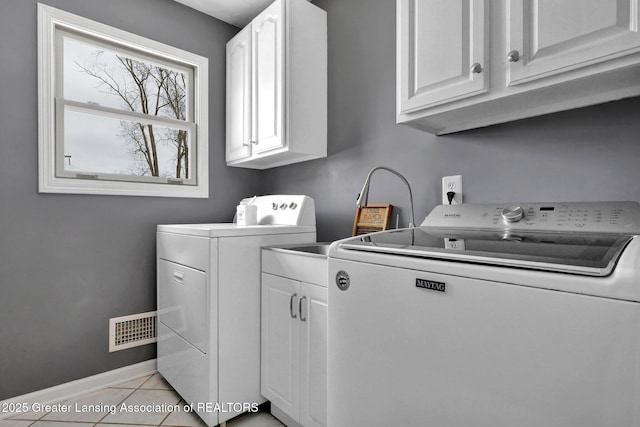 washroom with cabinets, light tile patterned floors, and washing machine and clothes dryer