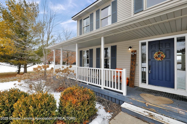 snow covered property entrance with a porch