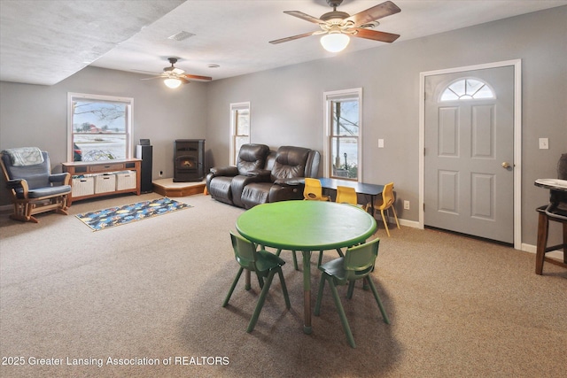 carpeted dining room featuring a wood stove and ceiling fan