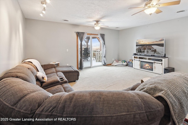 carpeted living room with a textured ceiling and ceiling fan