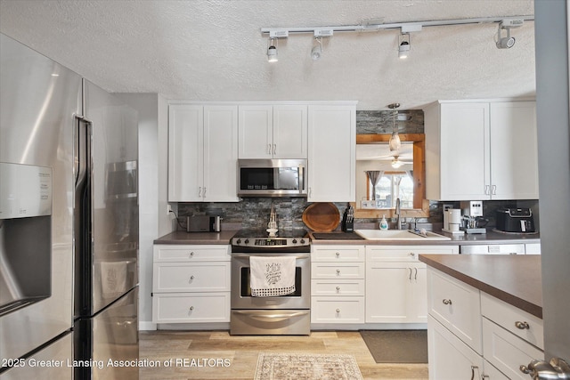 kitchen featuring sink, white cabinetry, backsplash, stainless steel appliances, and light wood-type flooring