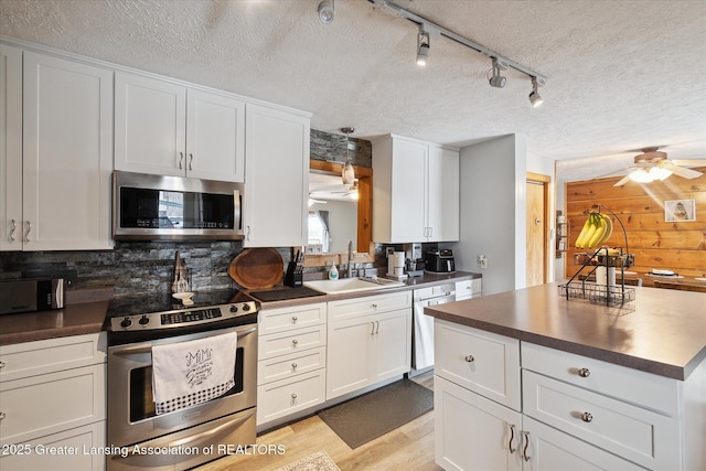 kitchen featuring appliances with stainless steel finishes, sink, white cabinets, and light hardwood / wood-style flooring