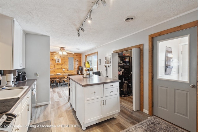 kitchen with a textured ceiling, light hardwood / wood-style floors, a center island, and white cabinets