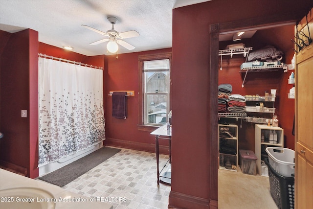 bathroom with ceiling fan and a textured ceiling