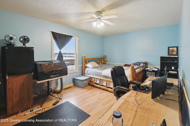 bedroom with ceiling fan, hardwood / wood-style floors, and a textured ceiling