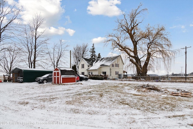 snow covered property with a storage shed and a carport