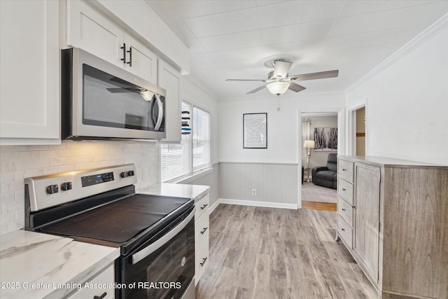 kitchen featuring light wood-type flooring, ornamental molding, white cabinets, and appliances with stainless steel finishes