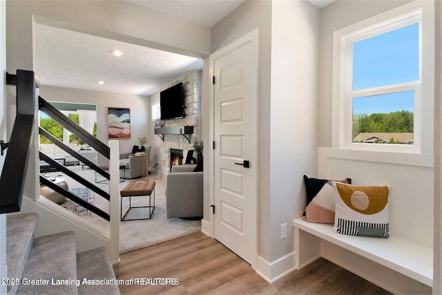 stairway with hardwood / wood-style flooring and a stone fireplace