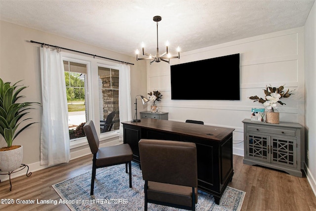 home office with wood-type flooring, a notable chandelier, and a textured ceiling