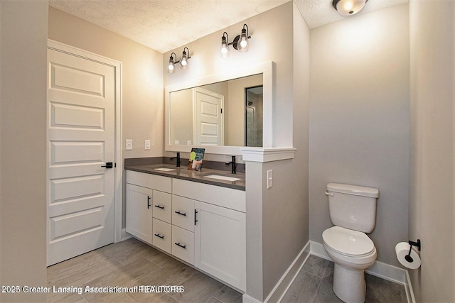 bathroom with vanity, hardwood / wood-style floors, toilet, and a textured ceiling