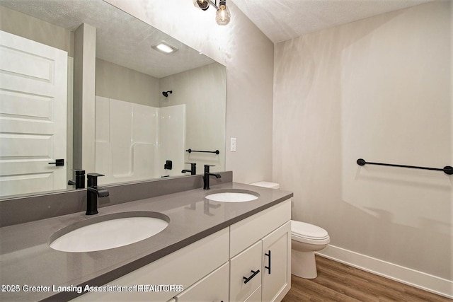 bathroom with walk in shower, toilet, a textured ceiling, vanity, and hardwood / wood-style flooring