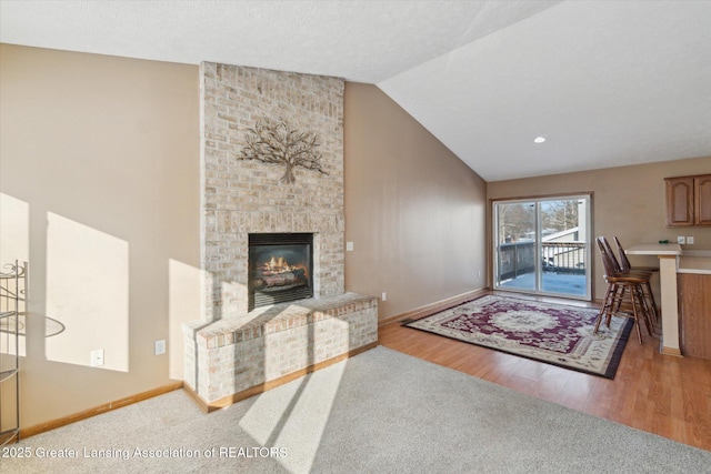 living room featuring a fireplace, high vaulted ceiling, and wood-type flooring