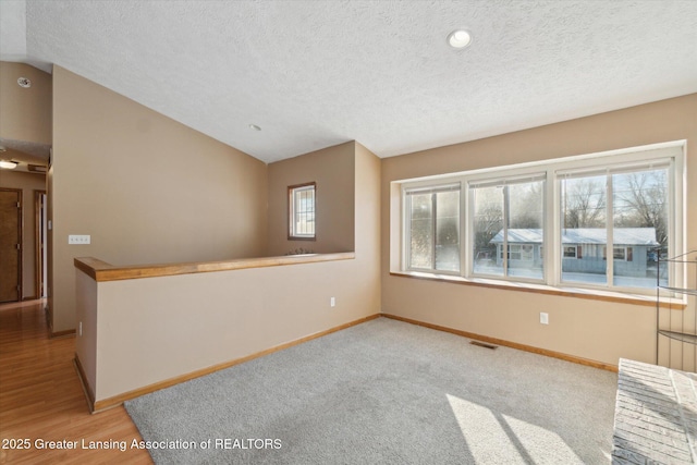 unfurnished room with vaulted ceiling and a textured ceiling