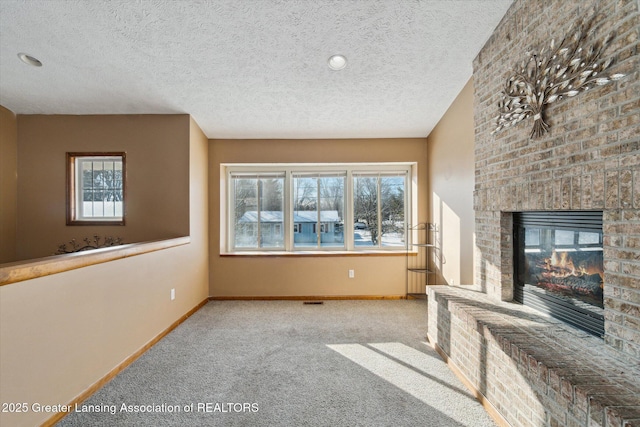 unfurnished living room featuring a fireplace, light colored carpet, and a textured ceiling