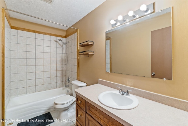 full bathroom with tiled shower / bath combo, vanity, a textured ceiling, and toilet