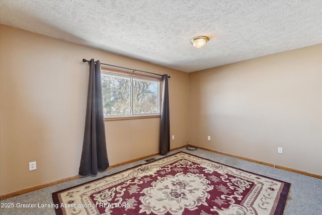 spare room with a textured ceiling and carpet