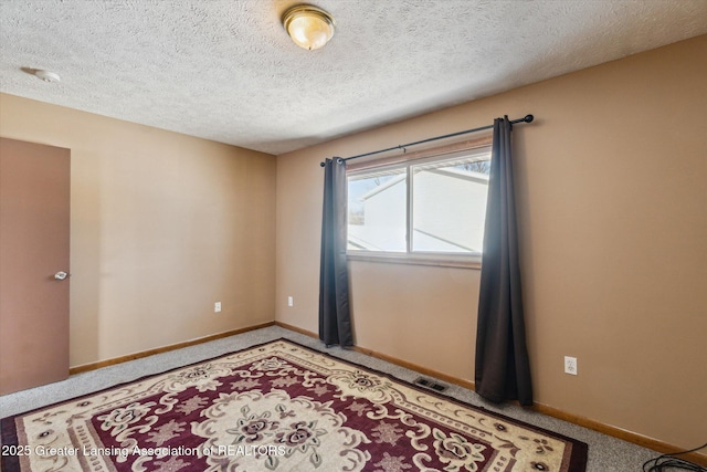 carpeted spare room with a textured ceiling