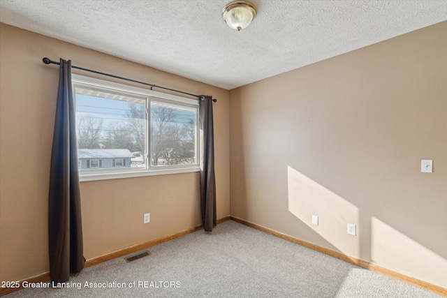 spare room featuring light carpet and a textured ceiling