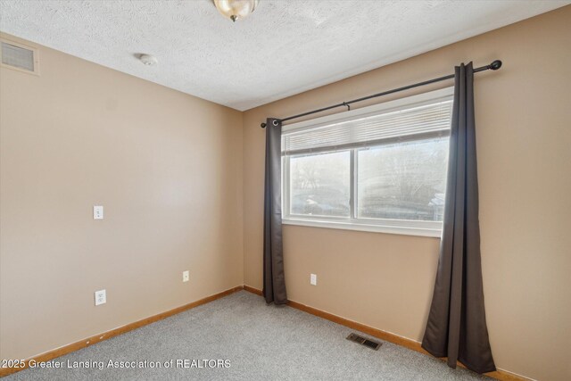 carpeted empty room with a textured ceiling