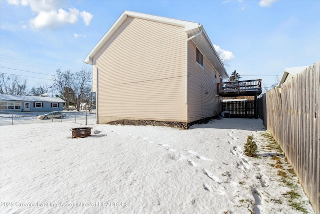 view of snowy exterior with a deck and an outdoor fire pit