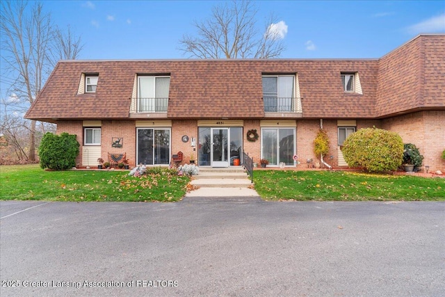 view of front of house with a balcony and a front yard