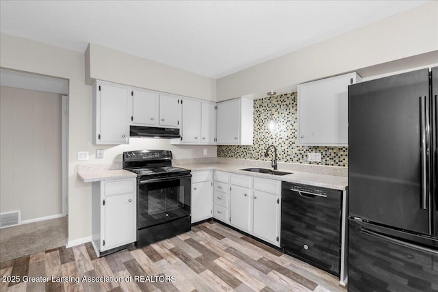 kitchen featuring white cabinetry, sink, decorative backsplash, black appliances, and light wood-type flooring