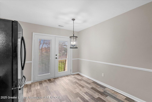 unfurnished dining area featuring french doors and light hardwood / wood-style flooring