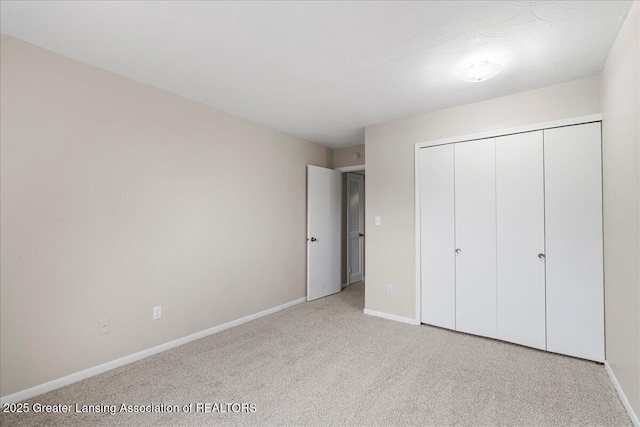 unfurnished bedroom featuring light colored carpet and a closet