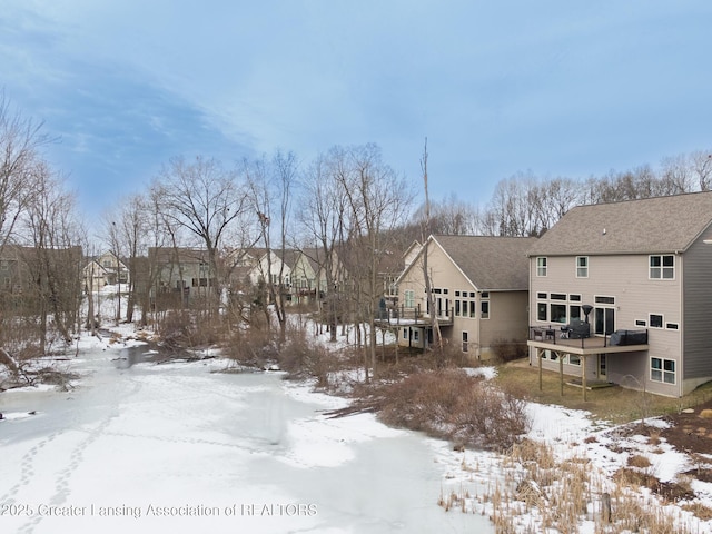 snow covered back of property with a wooden deck