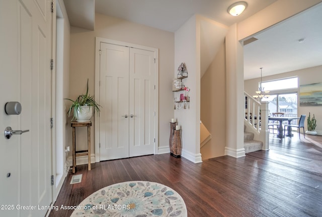 foyer with dark wood-type flooring and a chandelier