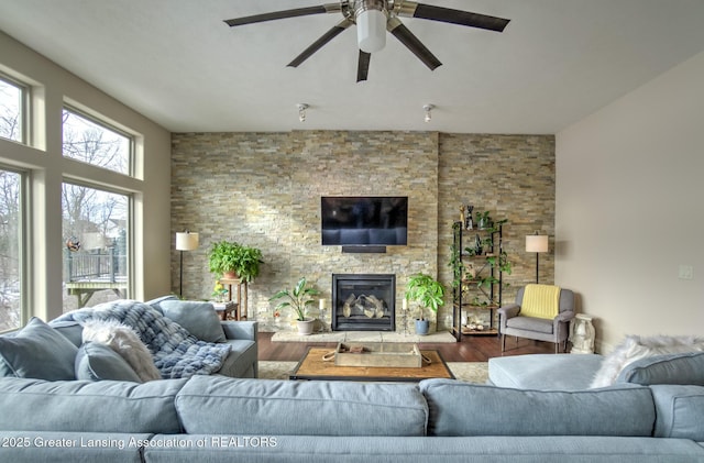 living room featuring wood-type flooring, ceiling fan, and a fireplace