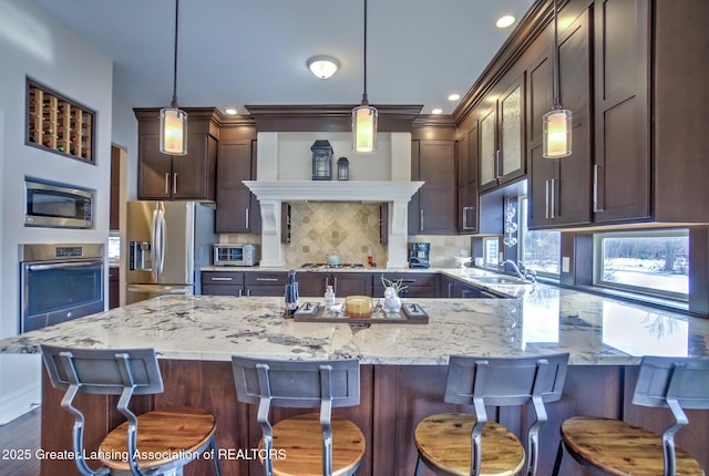 kitchen featuring a kitchen island, appliances with stainless steel finishes, pendant lighting, backsplash, and a kitchen breakfast bar