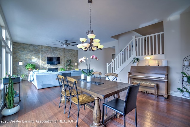 dining room featuring a fireplace, dark hardwood / wood-style flooring, and ceiling fan with notable chandelier