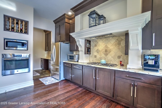 kitchen featuring light stone countertops, appliances with stainless steel finishes, backsplash, and dark hardwood / wood-style flooring