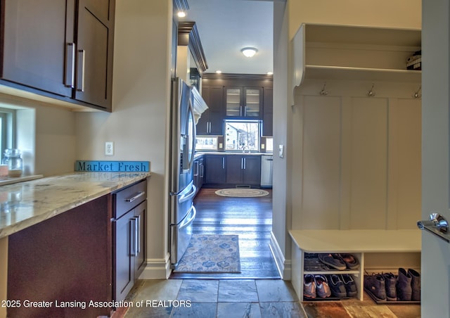 interior space with dark brown cabinetry, sink, light stone countertops, and appliances with stainless steel finishes