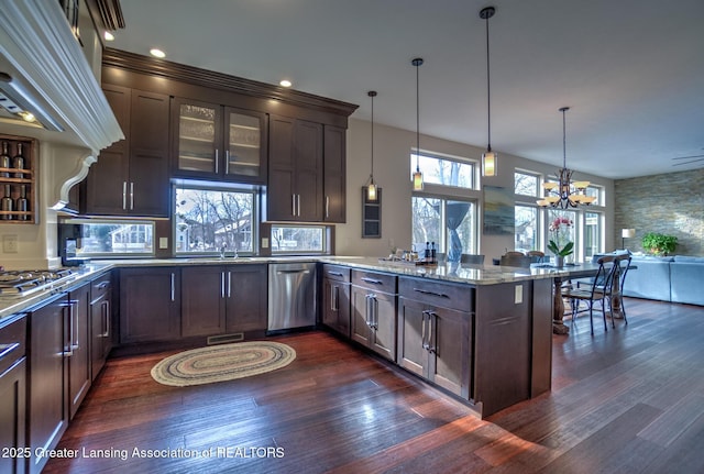 kitchen with decorative light fixtures, light stone counters, kitchen peninsula, stainless steel appliances, and dark brown cabinetry