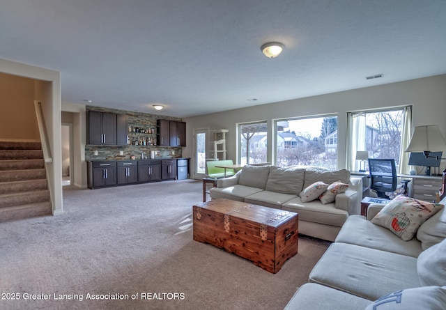 carpeted living room featuring bar and plenty of natural light