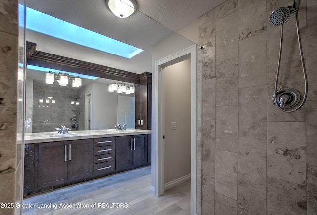 bathroom featuring vanity, a skylight, wood-type flooring, and a tile shower