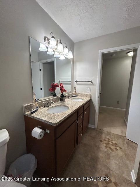 bathroom with vanity, a textured ceiling, and toilet