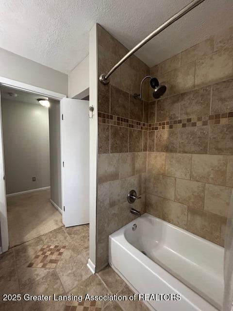 bathroom featuring tiled shower / bath combo and a textured ceiling