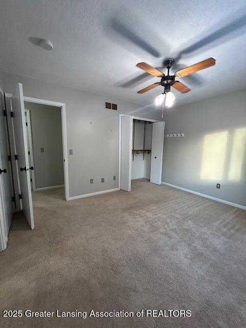 unfurnished bedroom featuring ceiling fan, carpet flooring, and a textured ceiling