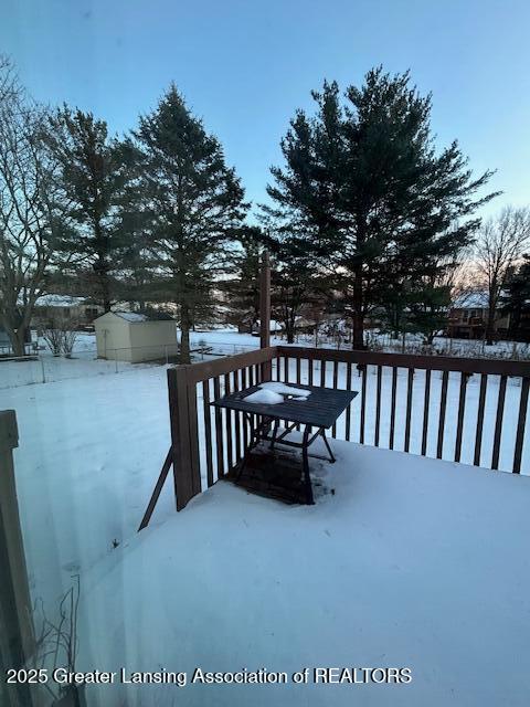 snow covered deck featuring a shed